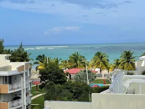 Ein Strandhotel mit mehreren Balkonen, Palmen und Blick auf den Ozean.