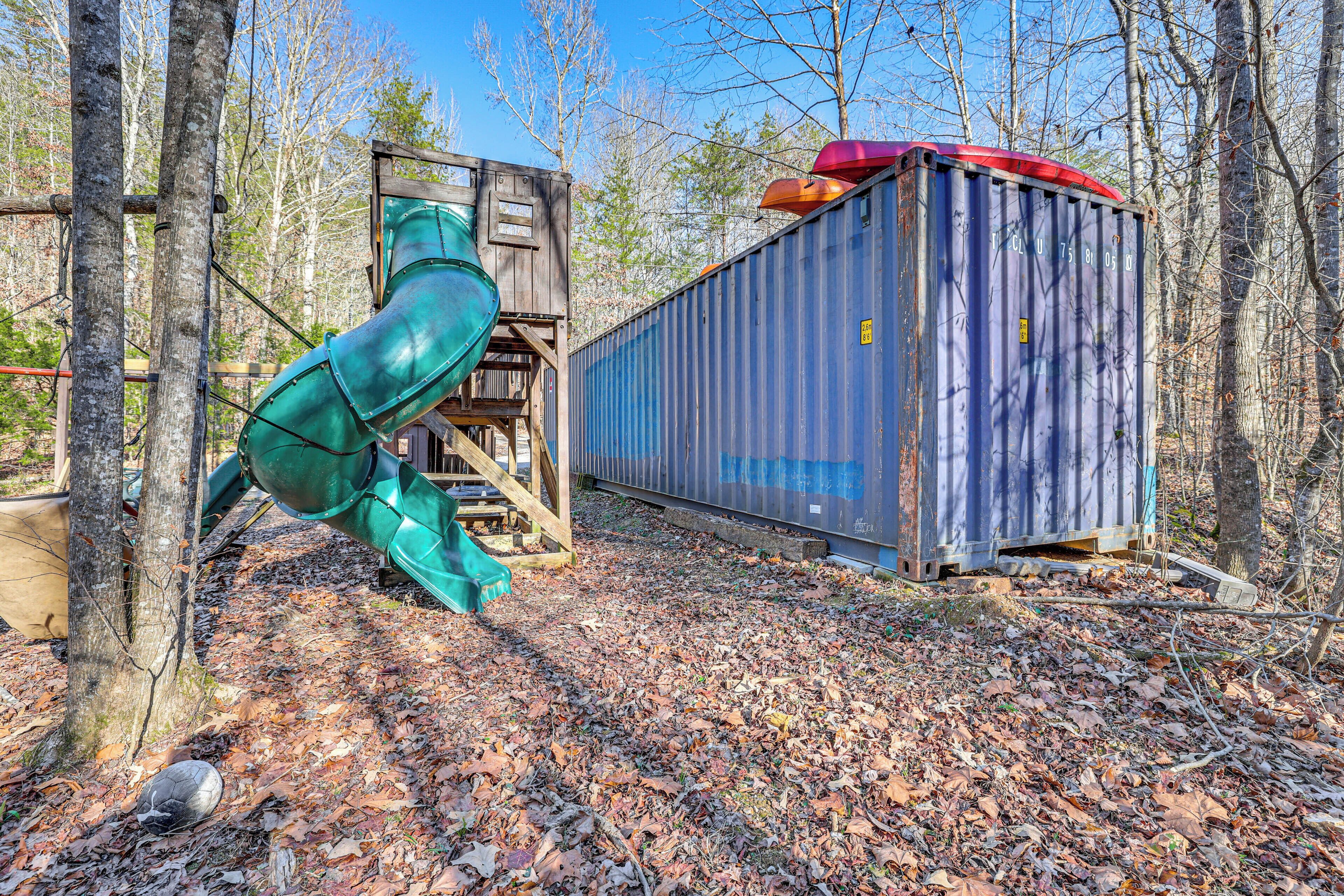 Eine rustikale Holzhütte mit einer Rutsche und einem Versandcontainer.
