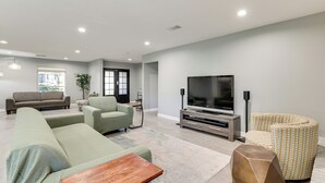 Una sala moderna con un sofá modular, una mesa de centro, un televisor y un sillón estampado.