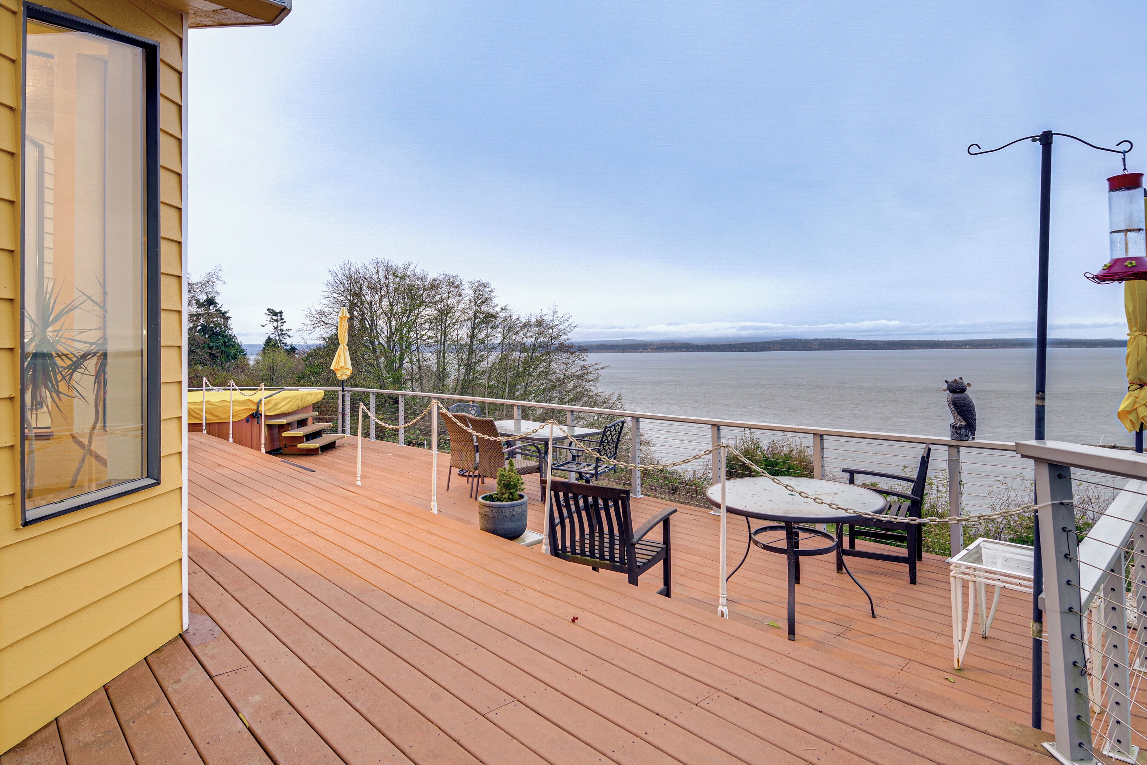 A wooden deck with outdoor furniture, a view of the water, and a statue.