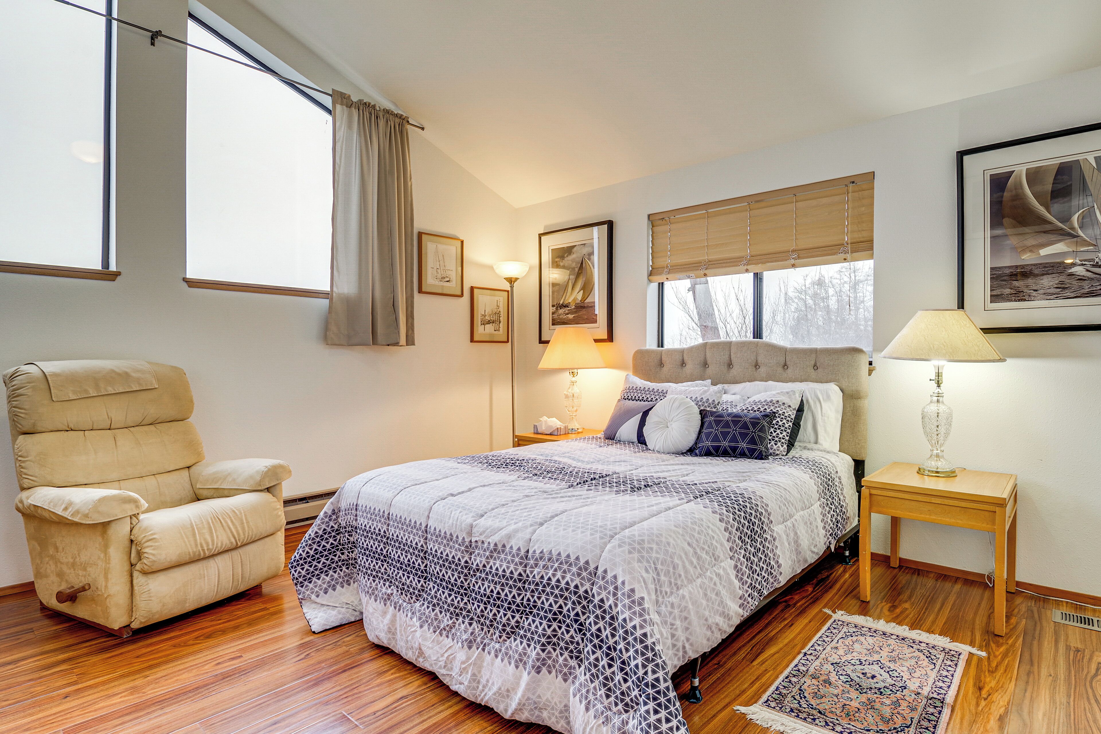 Une chambre à coucher avec un grand lit, une chaise, une table de chevet et une fenêtre avec des rideaux.