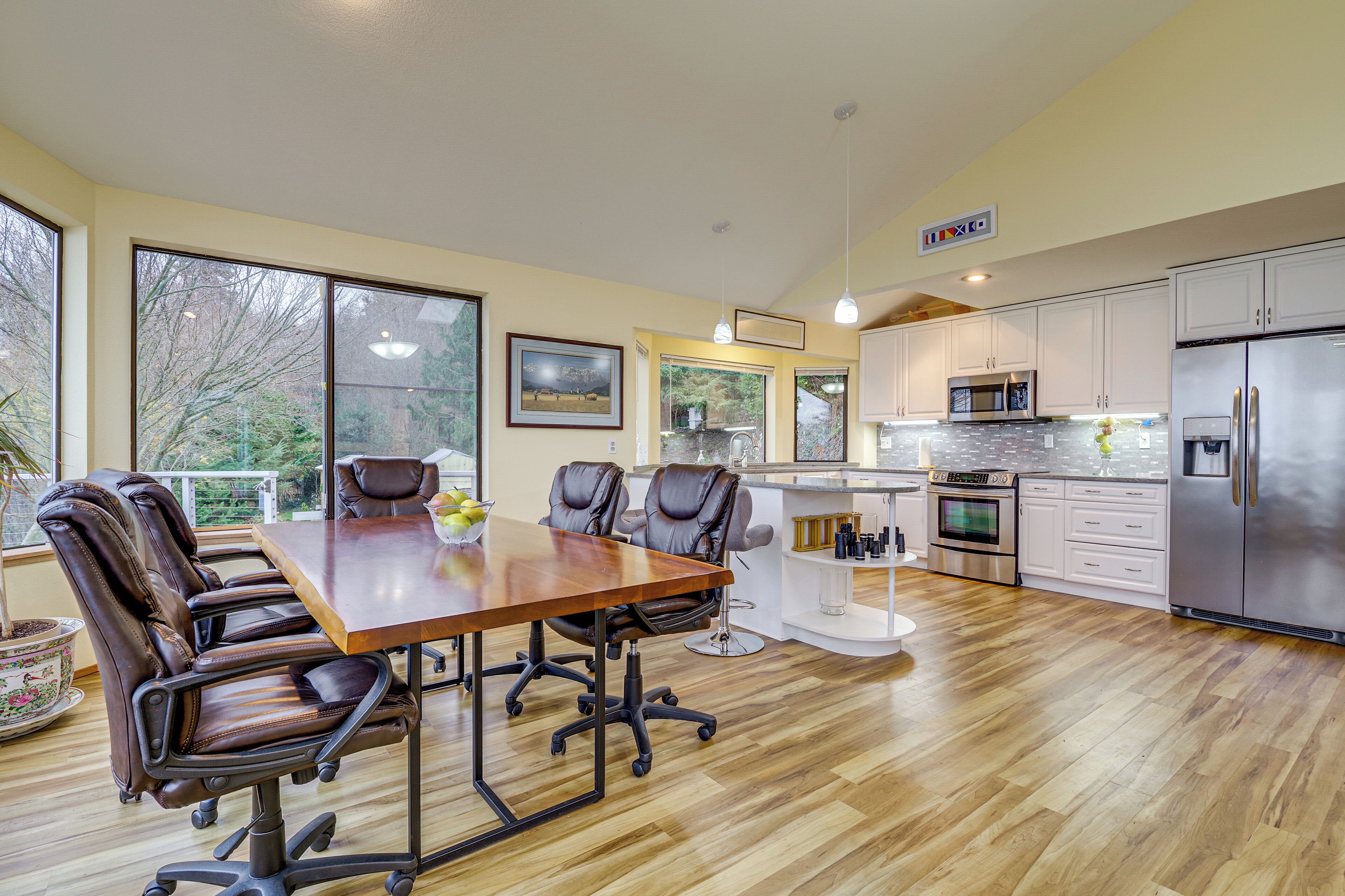 Una cocina moderna con una mesa de comedor de madera, sillas de cuero y electrodomésticos de acero inoxidable.