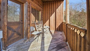 Eine Veranda mit Holzboden, einer Holztür, einem Fenster und einem Tisch mit Stühlen.