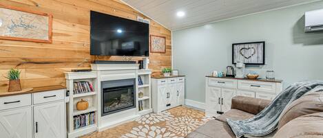 A cozy living room with a fireplace, a television, and a comfortable couch.