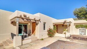 A stucco building with a stone patio, a covered entrance, and a small garden with red flowers. - Private Casita in the Foothills of Mt Lemmon! (Tucson)