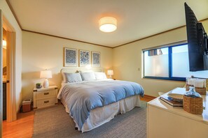 Ein Schlafzimmer mit einem Bett, Nachttischen, einem Schreibtisch und einem Fenster.