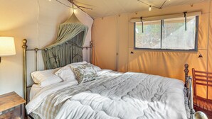 Una cama con dosel, una mesita de noche de madera, una ventana con vistas y una silla.