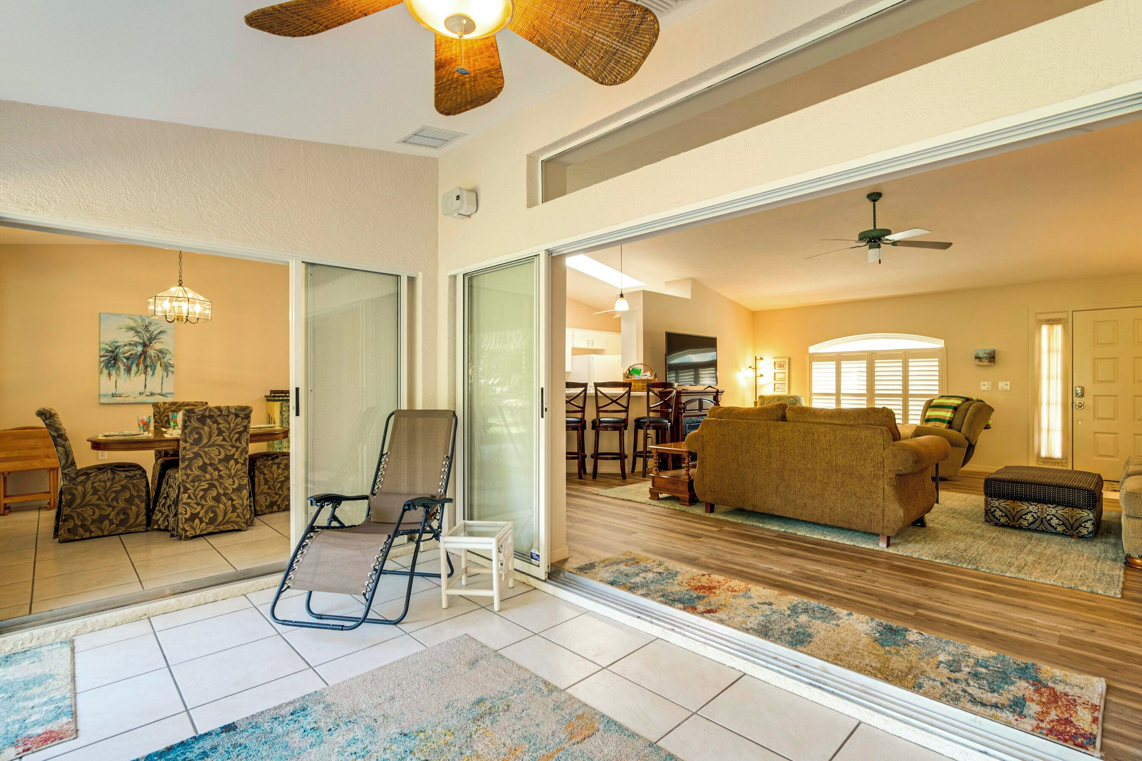 A spacious living room with a large mirror, a ceiling fan, and a dining area with patterned chairs.