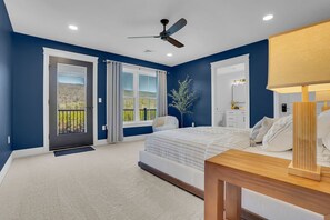 A bedroom with a bed, a nightstand, a ceiling fan, and a view of the outdoors through a sliding door.