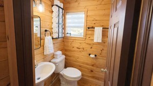 Een houten badkamer met een wastafel, toilet en handdoekhouder.
