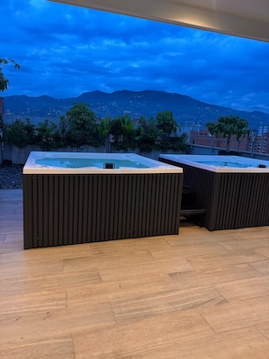 A rooftop terrace with two hot tubs and a view of the city and mountains. - Cozy 1-Bedroom Studio in marvelous Medellín with AC and Gym (Medellín)
