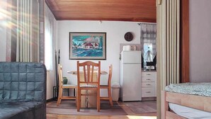 Un espace de vie compact comprenant un canapé, une table à manger avec des chaises, un réfrigérateur, une horloge et un tableau accroché au mur.