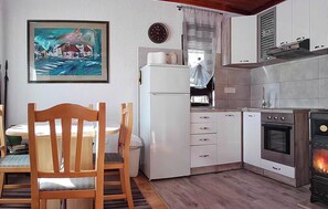 Une cuisine de taille réduite, équipée d’un réfrigérateur, d’une cuisinière et d’une table à manger en bois.