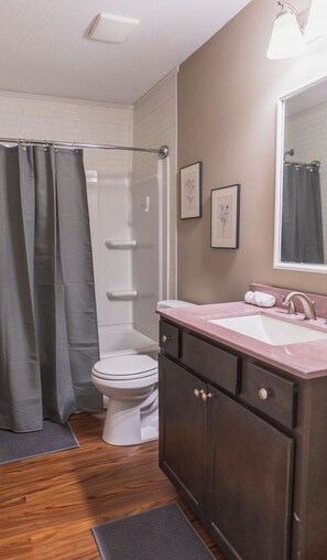 Une salle de bain équipée d’une douche, de toilettes, d’un meuble-lavabo et d’une œuvre d’art florale encadrée au mur.