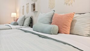 A neatly made bed with striped bedding and multiple pillows in various colors. - Anaheim, 2BR, modern guesthouse, Disneyland, sleeps 7, private entry & parking. (Anaheim)