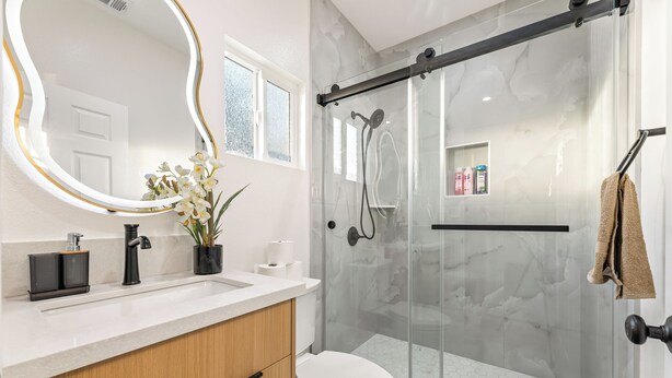 A modern bathroom with a glass shower enclosure, a white toilet, and a vanity with a mirror and sink. - Anaheim, 2BR, modern guesthouse, Disneyland, sleeps 7, private entry & parking. (Anaheim)