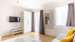 Une chambre à coucher avec un lit, une télévision, une armoire et une fenêtre avec des rideaux.
