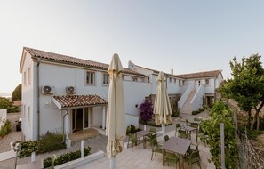 A two-story building with a tiled roof, outdoor seating area with tables and chairs, and a staircase leading to the upper floor. - Awesome apartment in Veli Losinj with WiFi (Veli Losinj)