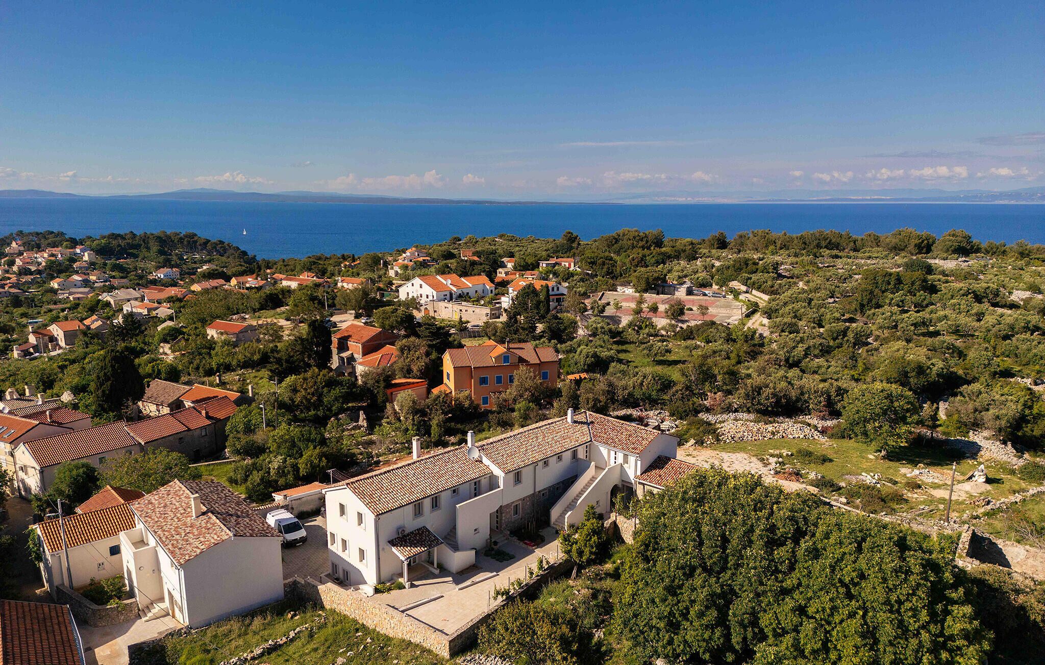 Un village côtier aux bâtiments aux toits de tuiles rouges, avec une église et une vue sur la mer.
