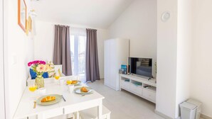 A modern, well-lit room with a dining table set for breakfast, a television, and a wardrobe. - 1 bedroom amazing apartment in Veli Losinj (Veli Losinj)