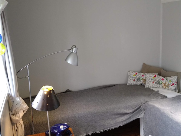 A bedroom with a bed, a desk, a lamp, and a window with curtains.