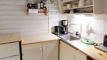 A kitchen with a sink, coffee maker, and a green stool.