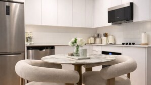A modern kitchen with white cabinetry, a stainless steel refrigerator, a built-in oven, and a flat-screen TV mounted above the counter. - Fully Furnished Stylish Vaughan Condo near / Steps to VaughanMills (Vaughan)