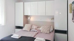 A bedroom with a bed, two pillows, a nightstand, and a white wardrobe. - Lovely apartment in Rab with WiFi (Rab)