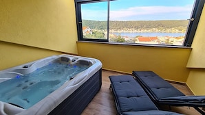A room with a hot tub, a massage table, and a window with a view of a lake and buildings. - 2 bedroom nice apartment in Rab (Rab)