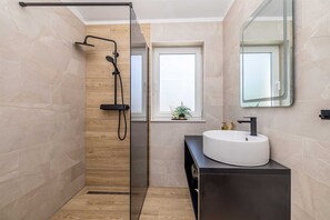 A modern bathroom with a glass shower enclosure, a white sink, and a window with a plant. - Villa LA VIE with private pool (Garica)