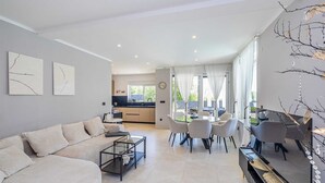 A modern living room with a sofa, coffee table, and dining area with chairs. - Villa LA VIE with private pool (Garica)