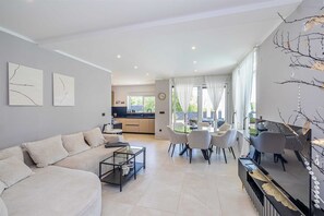 A modern living room with a sofa, coffee table, and dining area with chairs. - Villa LA VIE with private pool (Garica)