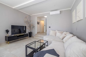 A modern living room with a sofa, a glass coffee table, a TV, and a decorative plant. - Villa LA VIE with private pool (Garica)