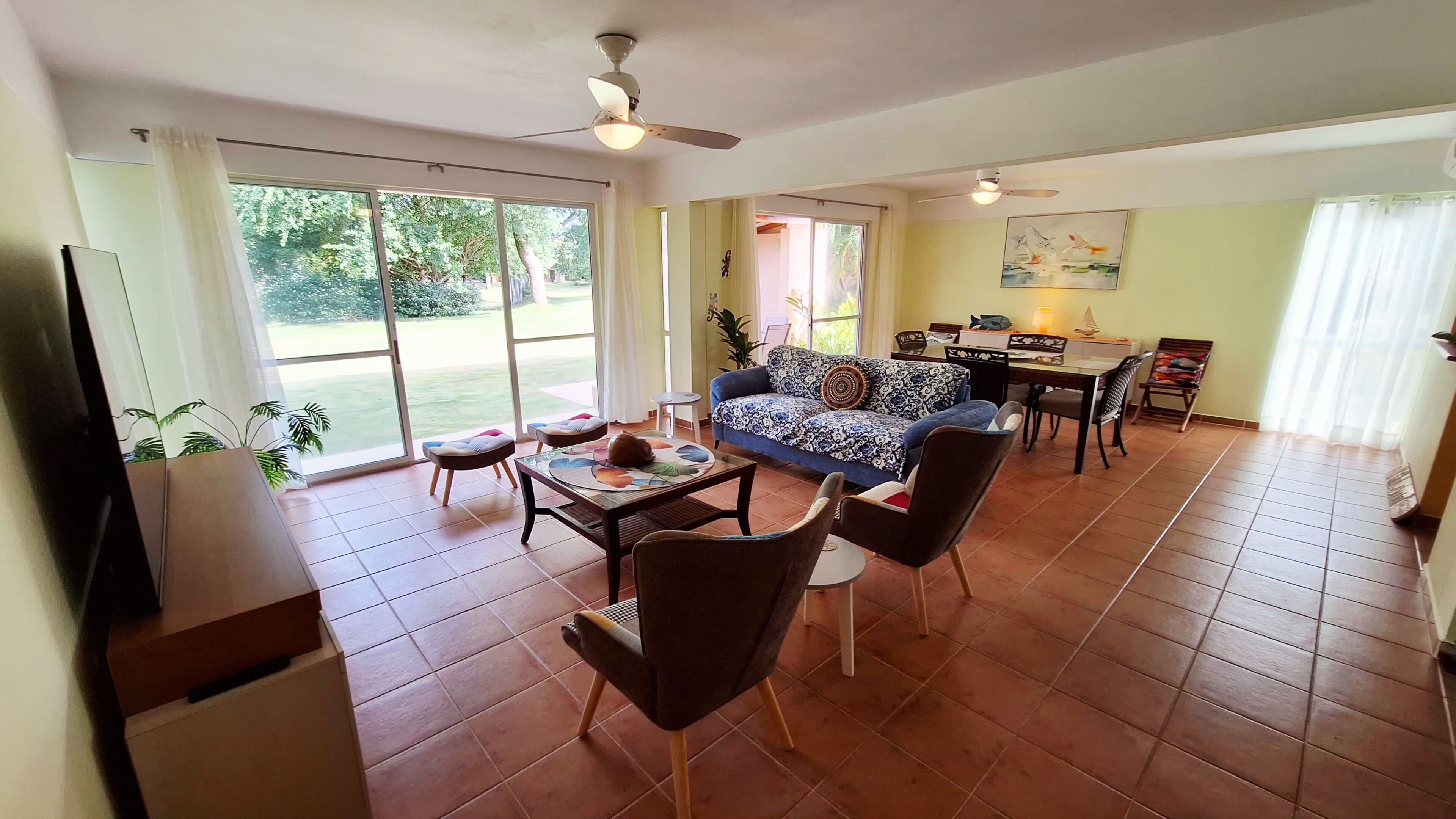 Un amplio espacio de sala con un sofá, sillas, una mesa de comedor y un televisor.