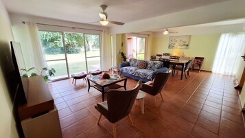 Un amplio espacio de sala con un sofá, sillas, una mesa de comedor y un televisor.