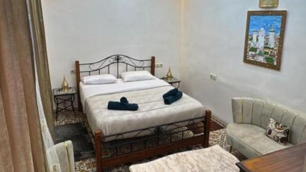 Een slaapkamer met een bed, nachtkastjes, een bank en een schilderij aan de muur.