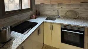 Een keuken met een granieten aanrecht, een ingebouwde oven, een spoelbak en een raam met geëtste glas.