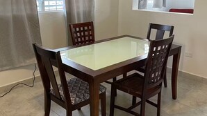 A dining area with a rectangular glass-top table surrounded by four wooden chairs with patterned cushions. - New in market, Hato Rey 2 bedrooms -301- (San Juan)