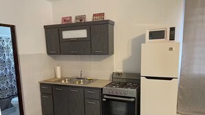 A compact kitchen with dark cabinetry, a gas stove, a microwave, and a built-in oven. - New in market, Hato Rey 2 bedrooms -301- (San Juan)