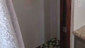Un couloir étroit avec une porte donnant sur une salle de bain. Le couloir est doté d’un sol carrelé et d’un chambranle en bois.