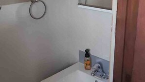Une salle de bain avec un lavabo blanc, un miroir et un porte-serviette.