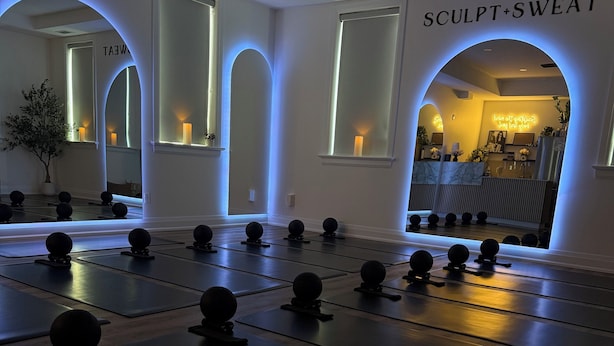 A yoga studio with mats and balls, a mirror, and a sign reading 'Sculpt+Sweat'. - Brand New! Downtown Stratford: The Blowes Inn 3C: 2 Bedrooms (Stratford)