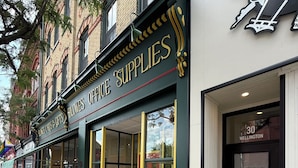 A storefront with a sign reading 'Blondes Office Supplies' and a door with a window displaying a sign for '30 Wellington Inn'. - Brand New! Downtown Stratford: The Blowes Inn 3C: 2 Bedrooms (Stratford)
