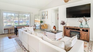 Un salon moderne comprenant un ensemble de canapés, une table basse, un téléviseur et un ventilateur de plafond.