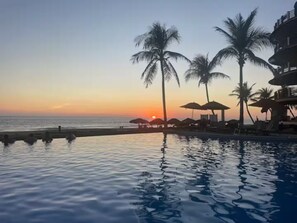 A poolside view with palm trees and a sunset. - Beautiful Ocean view 2 BD Condo (Bajos de Chila)