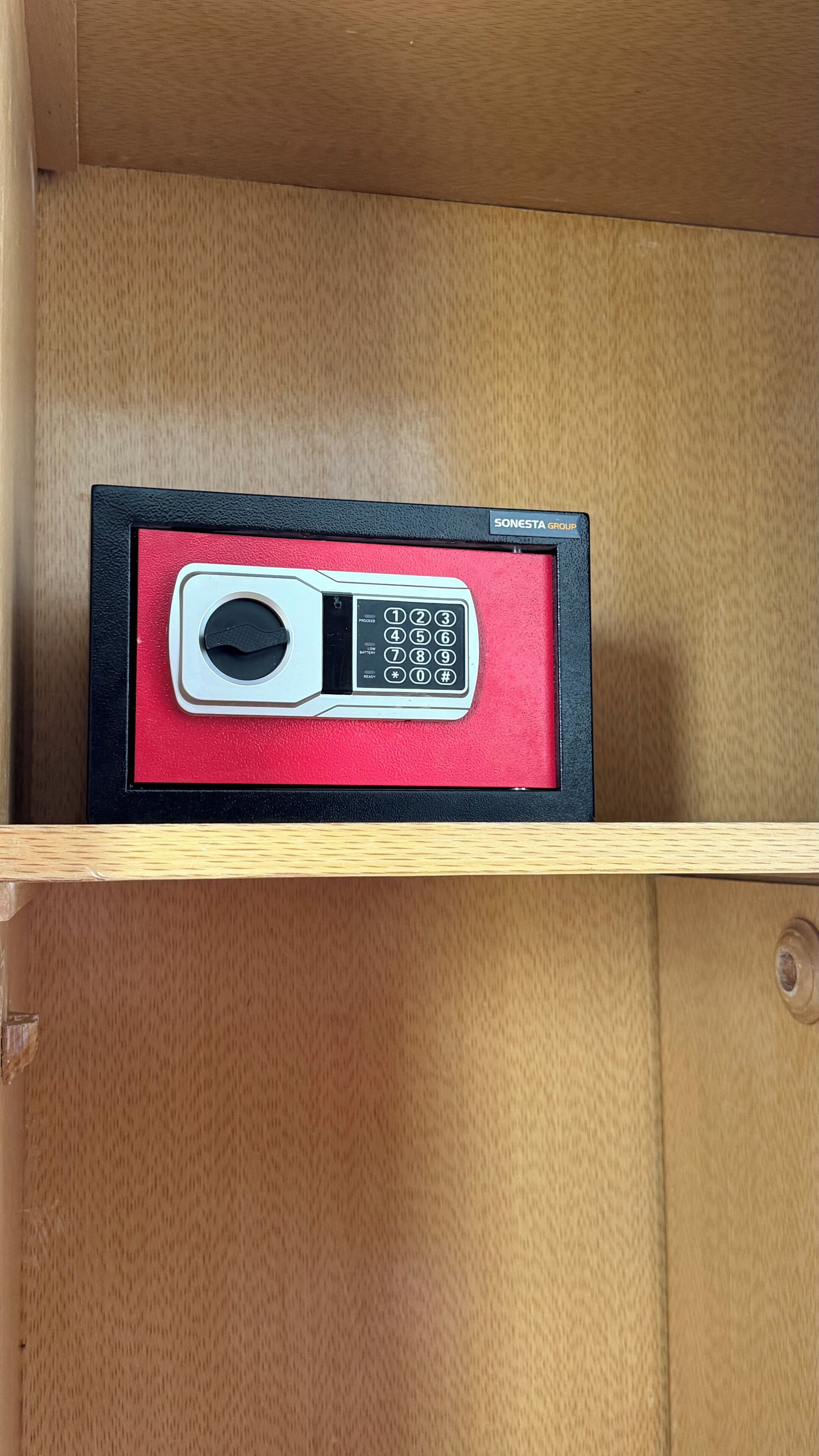 A SONESTA GROUP mobile phone in a red and black box on a wooden shelf.