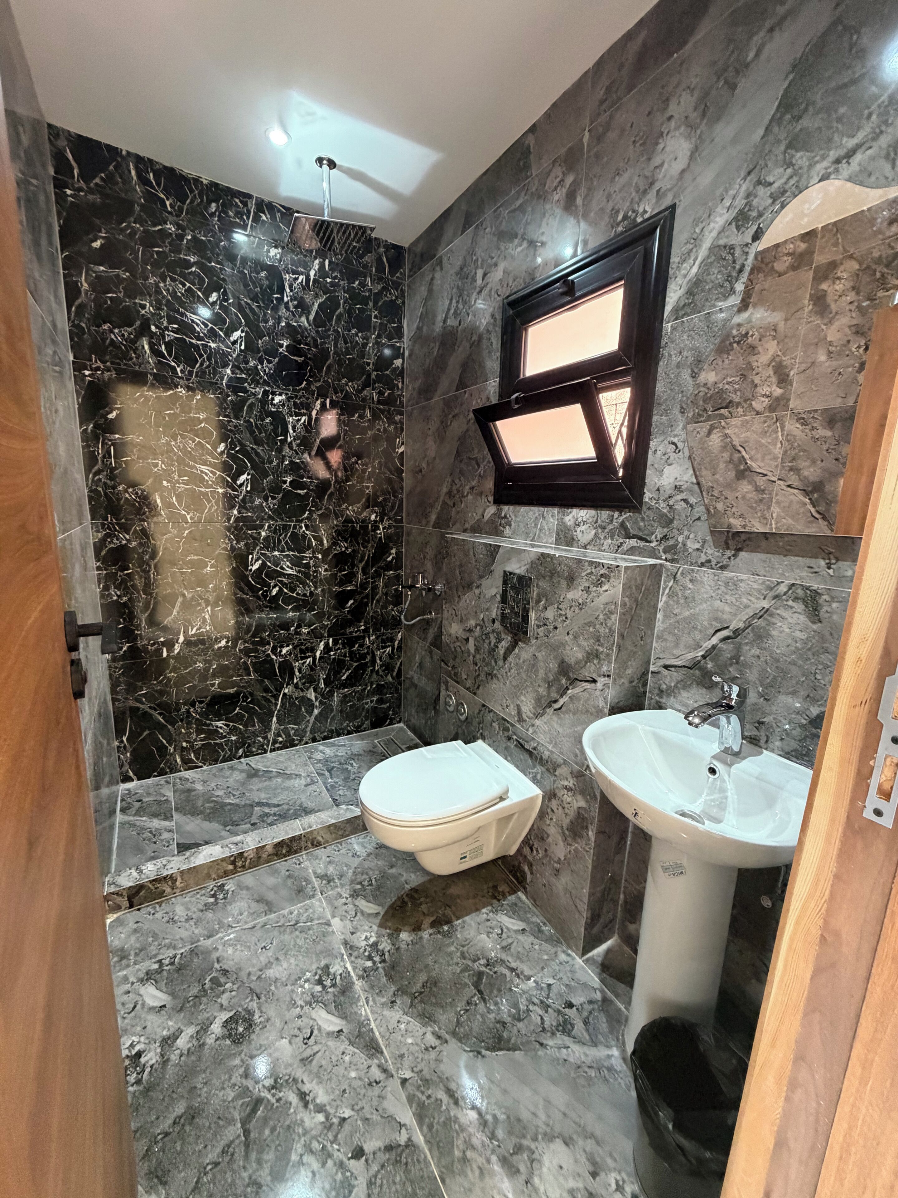 Un baño con piso de mármol, inodoro, lavamanos y ducha.