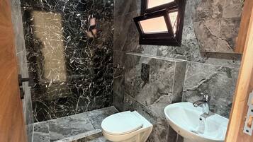 Un baño con piso de mármol, inodoro, lavamanos y ducha.