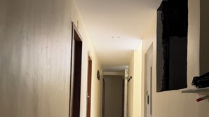 Un couloir doté d’un sol en marbre, avec des portes de part et d’autre, et une fenêtre sur le côté droit.