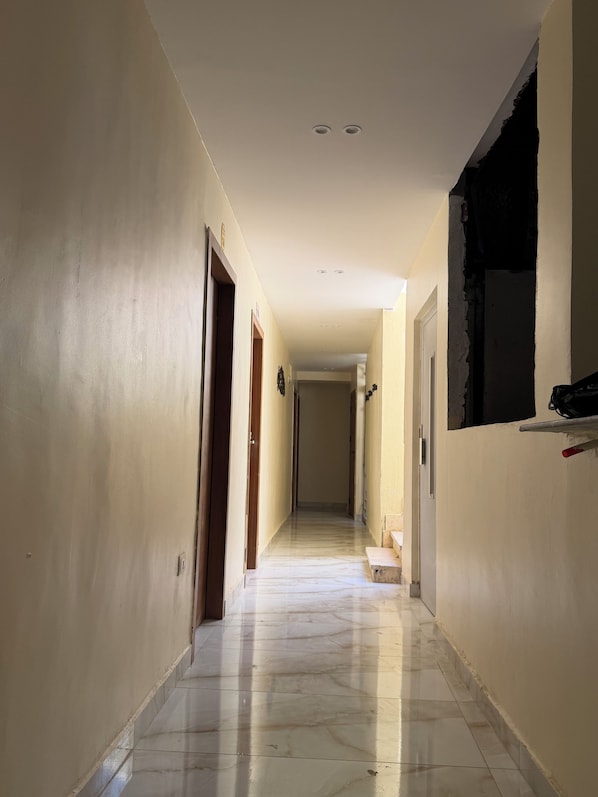 A hallway with a marble floor, doors on both sides, and a window on the right. - Amon Ra Hotel (Giza)